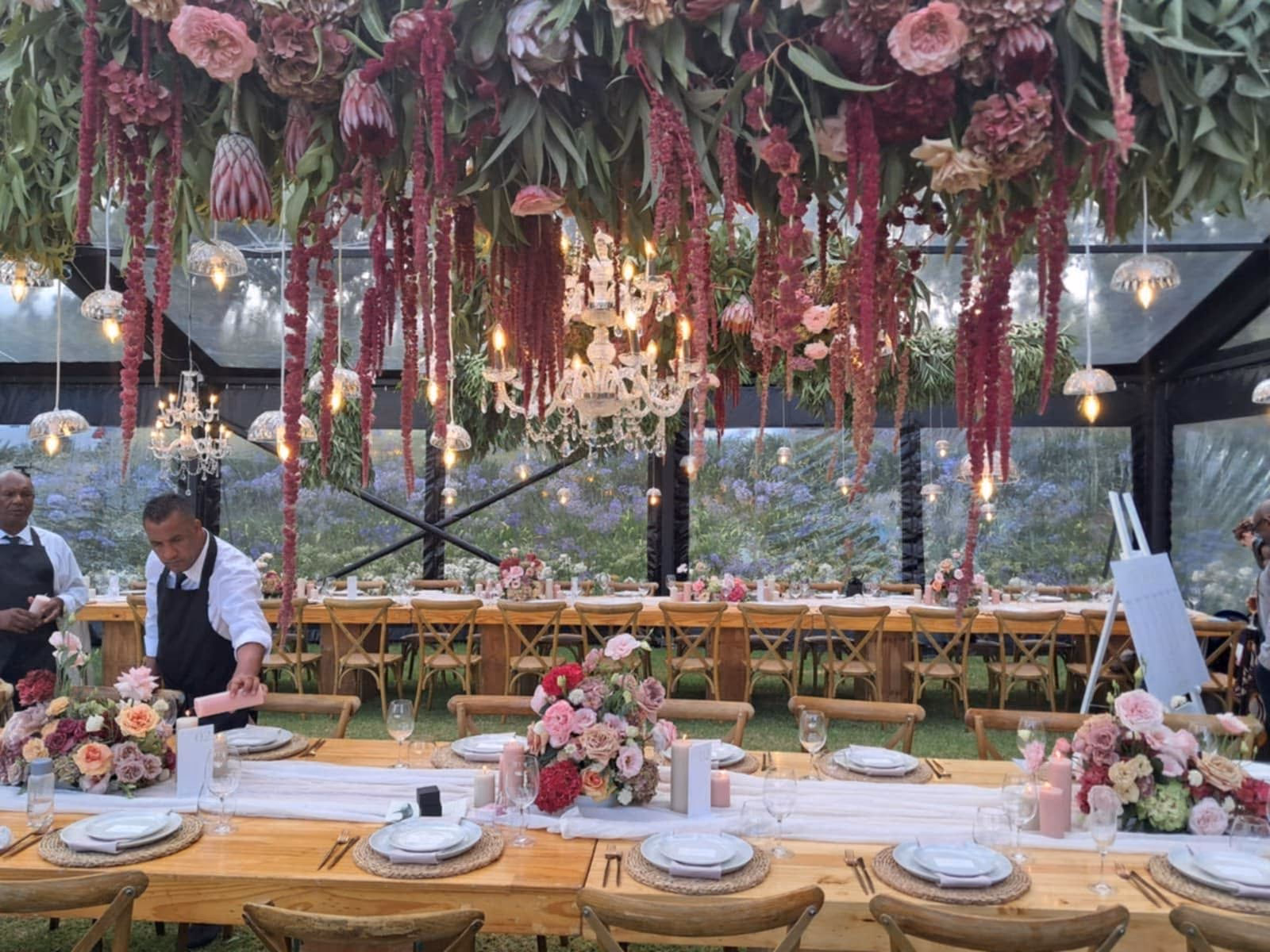 A richly layered floral installation above a wedding reception