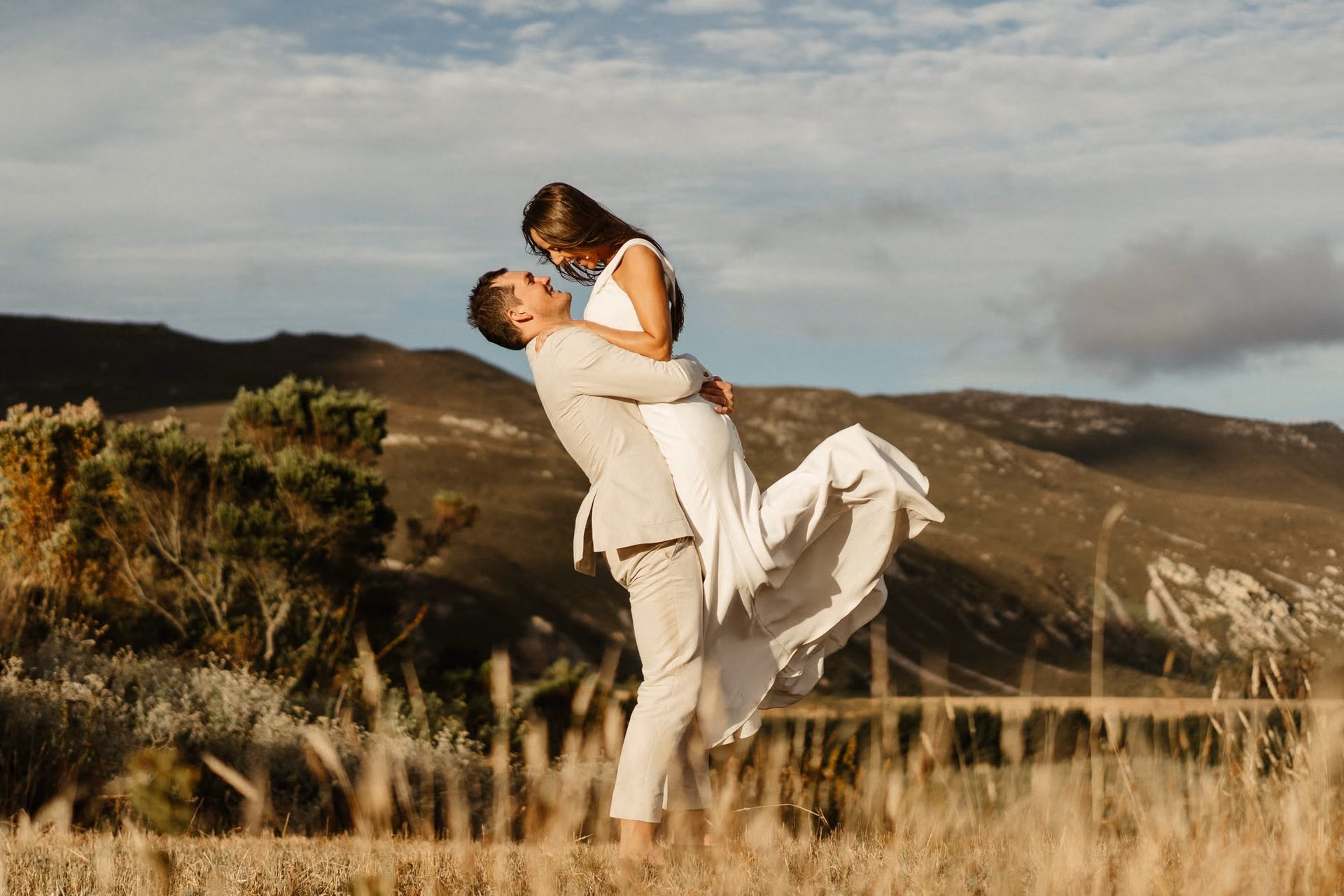 A couple embracing in the fynbos with the Hemel-en-Aarde mountains behind them