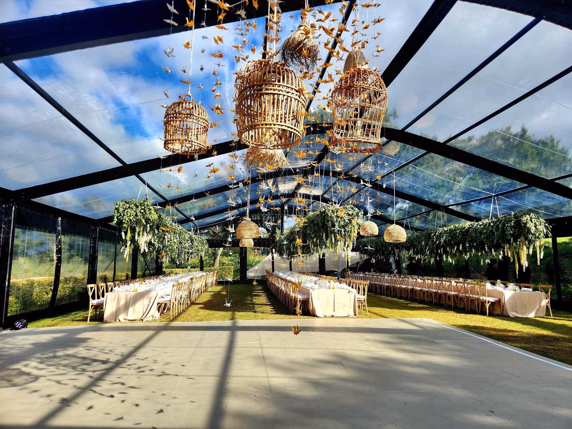 A glass reception structure dressed with woven lights and suspended birds
